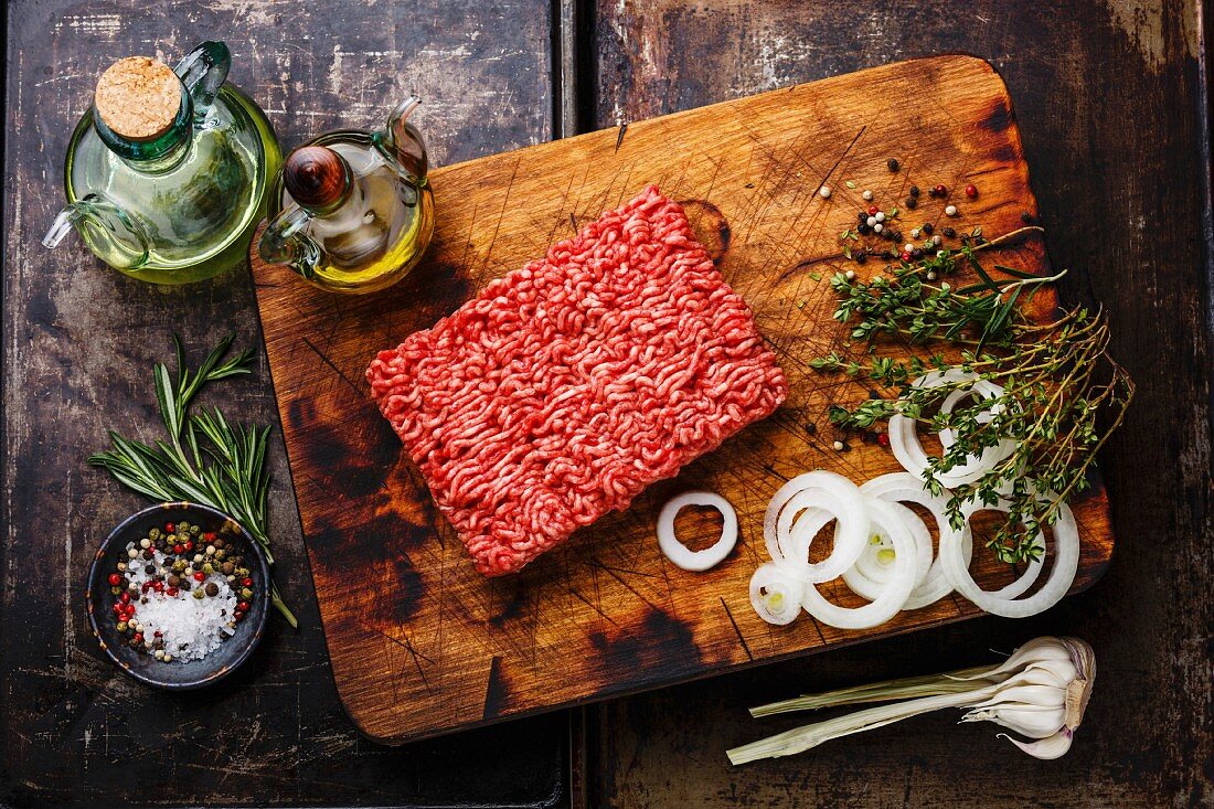 Raw fresh Minced ground meat and condiments on dark background