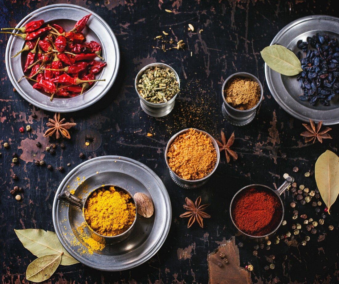 Set of spices pepper, turmeric, anise, coriander in vintage metal cups over old wooden table