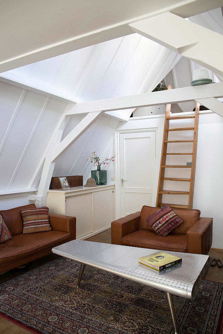 Cognac leather seating in living room with ladder leading to gallery in roof space