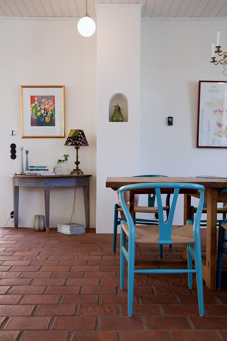 Blue designer chair at dining table on terracotta floor tiles