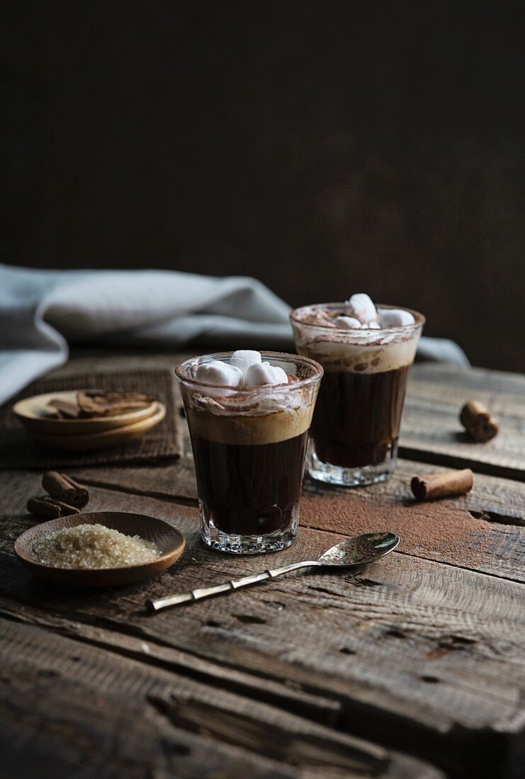 Kaffee mit Sahne und Marshmallows auf rustikalem Holztisch