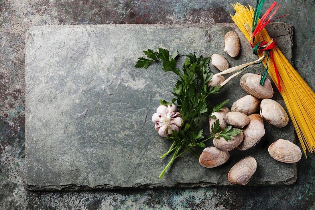 Ingredients for cooking Spaghetti vongole Shells vongole and raw sapaghetti on stone slate background