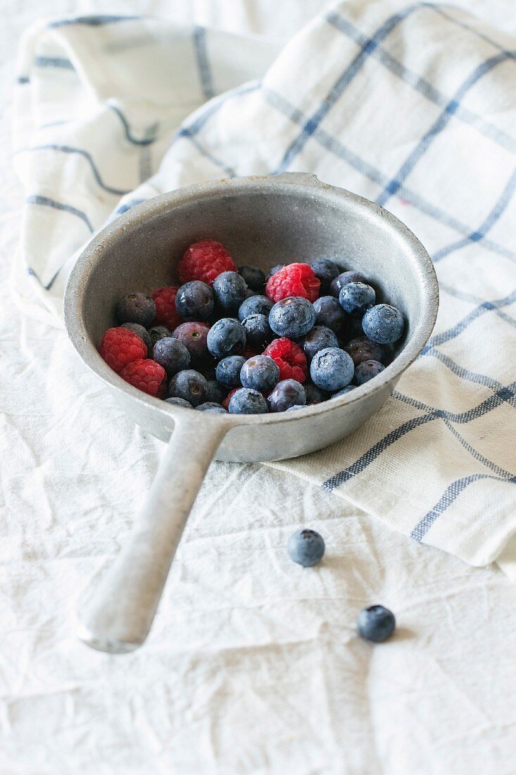 Aluminum colander with fresh raspberries and blueberries