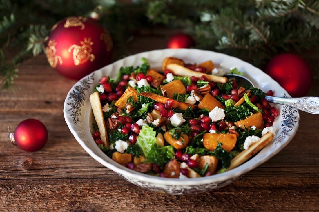 Festive savoy cabbage, roasted sweet potatoes and parsnips salad with Feta cheese, pecans and pomegranate in a bowl