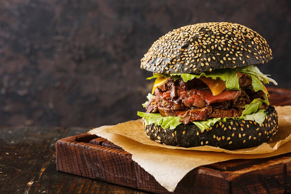 Roast beef Burger on sesame bun with sliced Pastrami on black background