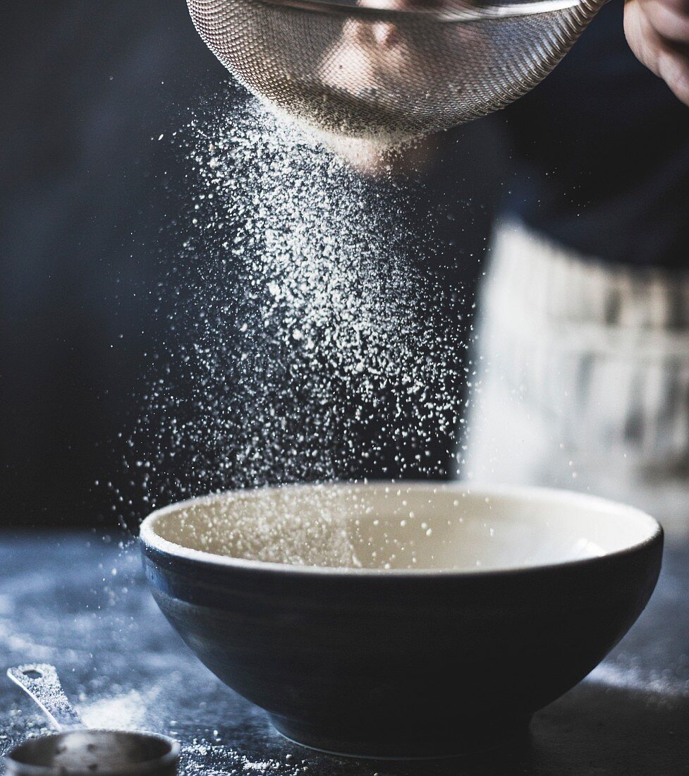 Flour being sieved into a bowl