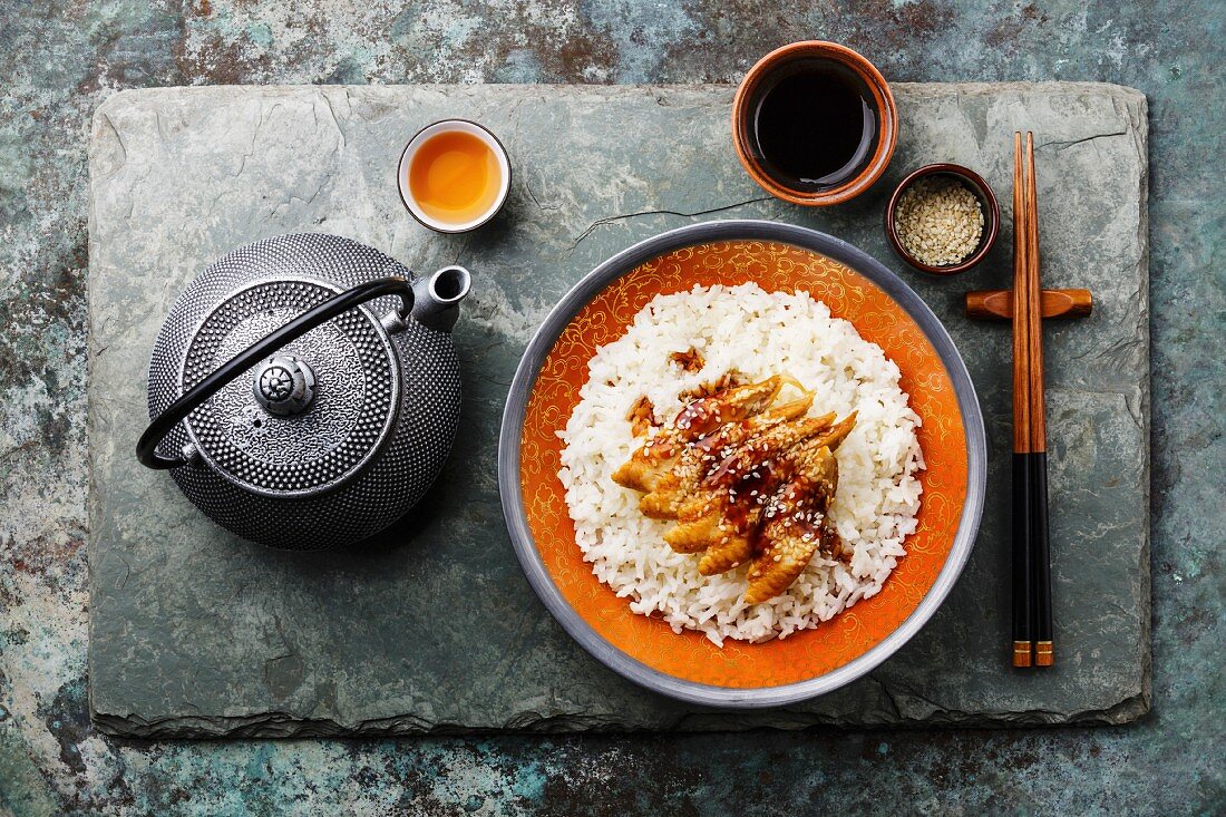 Eel with sauce and sesame on Rice and green tea on stone slate background