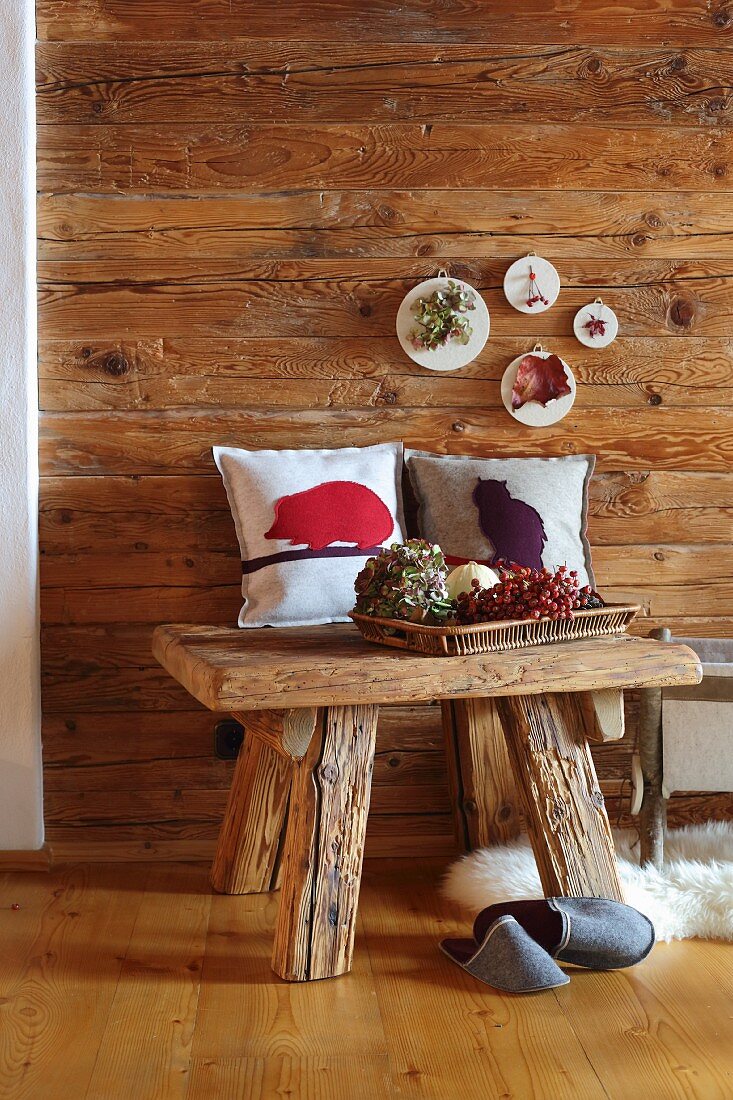 Small artworks made from felt remnants on wooden wall and cushion covers with felt motifs in cabin-style interior