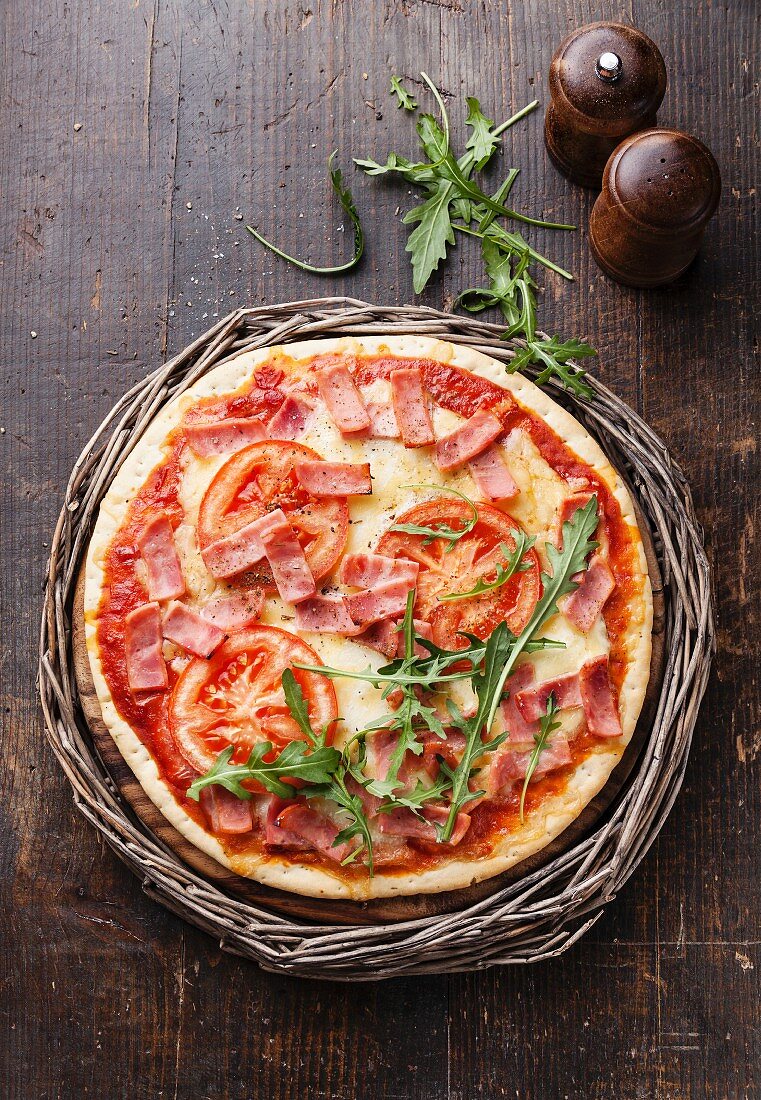 Pizza mit Schinken, Tomaten und Rucola