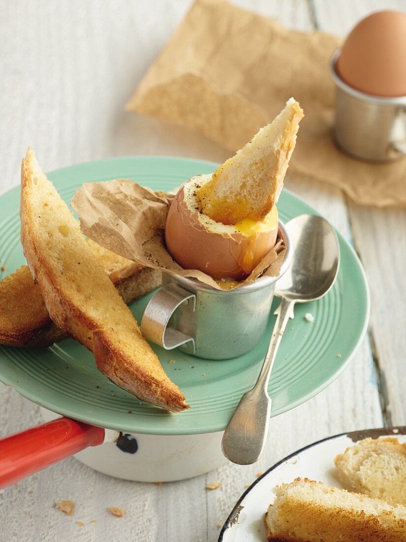 Boiled egg and soldiers on vintage plate with silver spoon