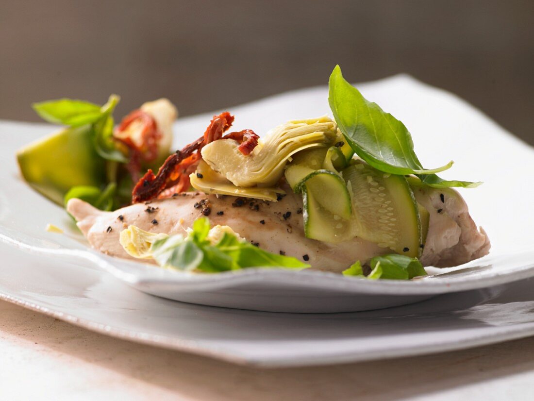 Chicken fillet cooked in foil with artichokes, tomatoes and zucchini