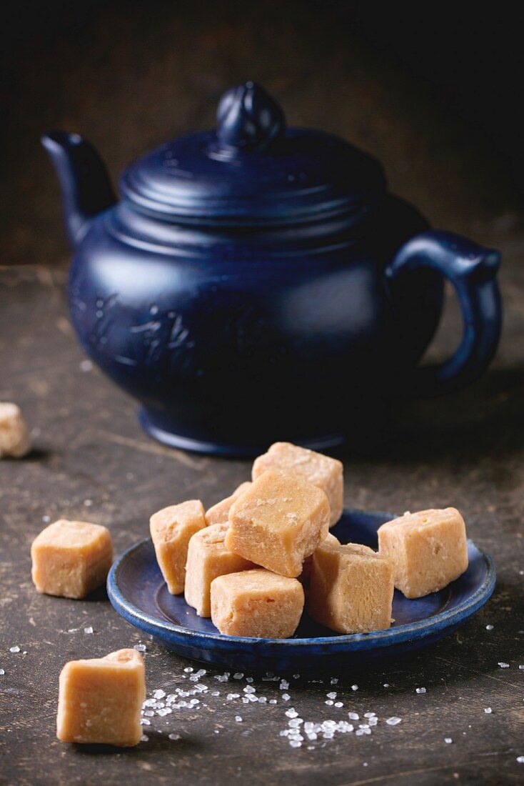 Fudge (Karamellbonbons) auf Teller, im Hintergrund Teekanne