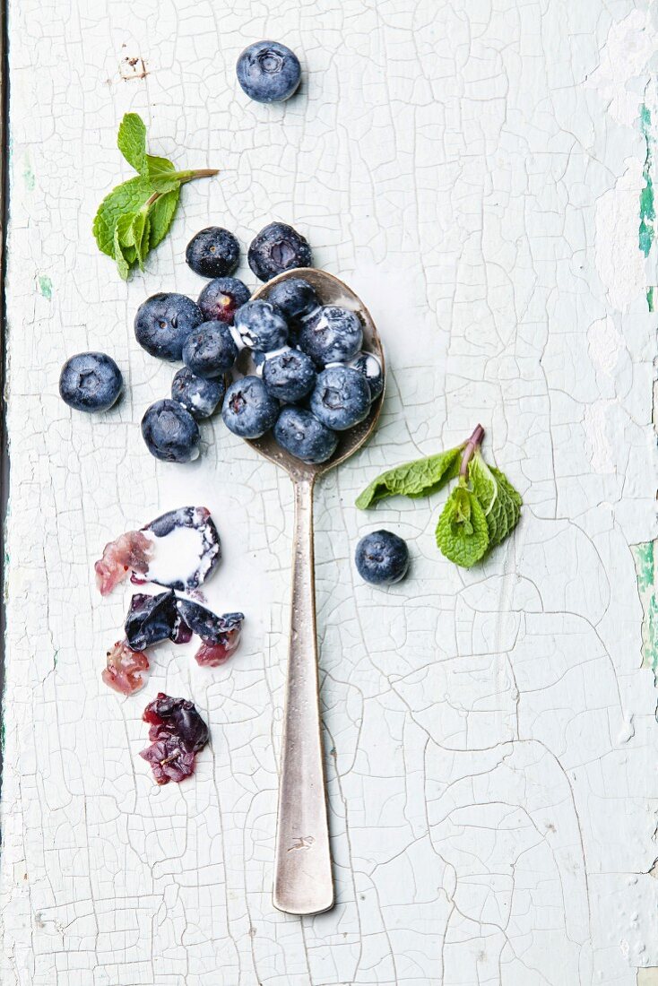 Ripe blueberries in spoon on textured background