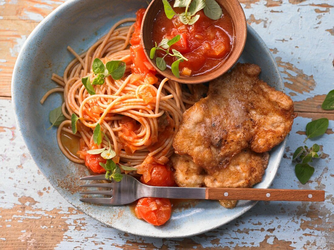 Chicken breast slices in a cheese coating with noodles and tomatoes