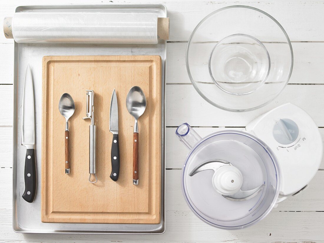 Various kitchen utensils: blender, glass bowls, knives, spoons, peeler