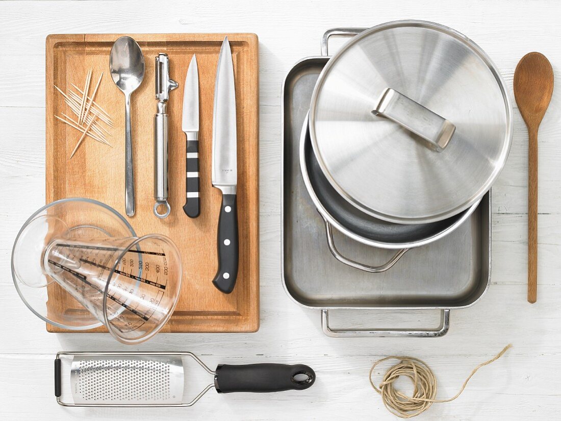 Various kitchen utensils: pot, baking dish, grater, kitchen string, measuring cup, knife, toothpick