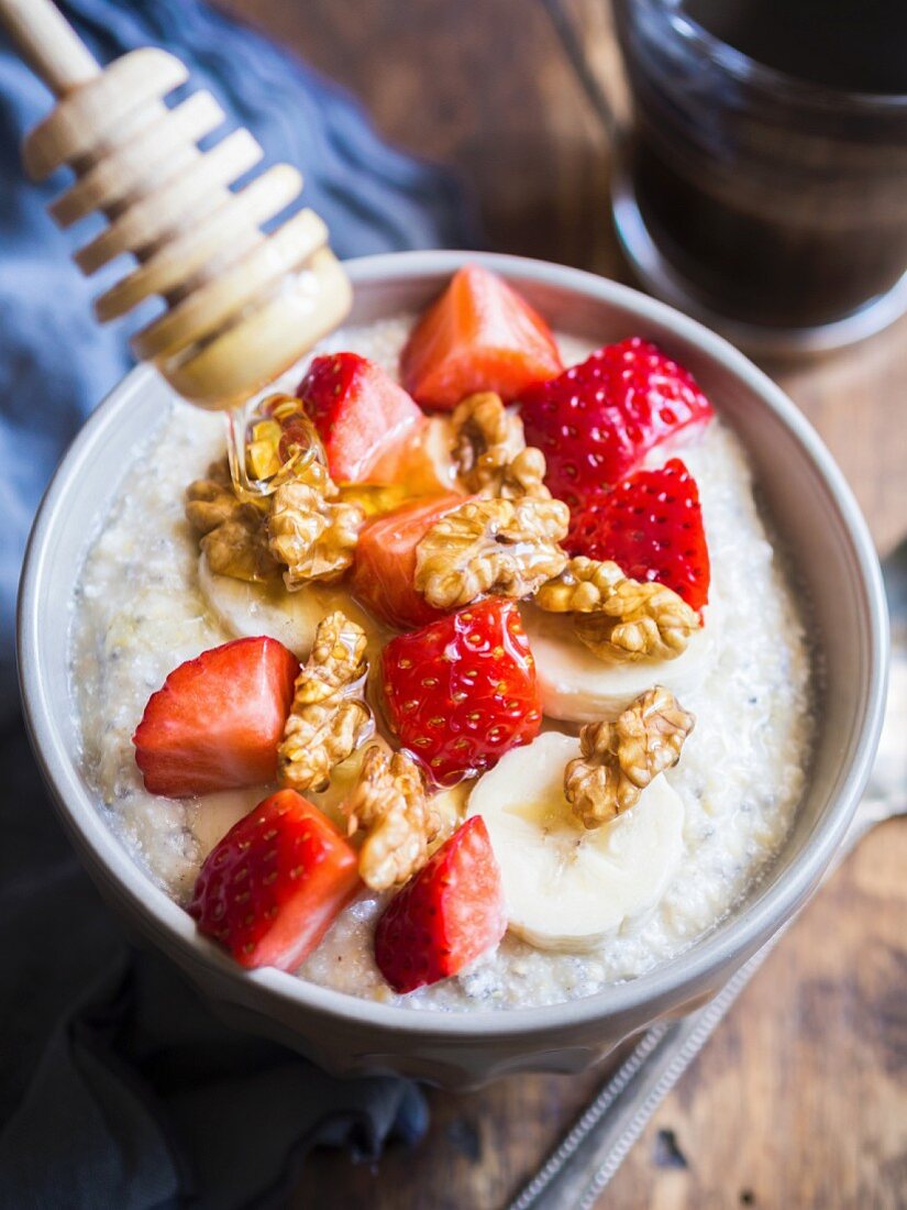 Healthy breakfast: oatmeal porigge with coco, chia seeds, nuts, fresh fruit and honey