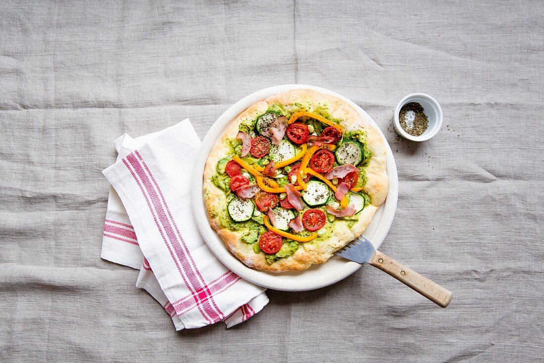 Pizza mit Avocado, Zucchini, Tomaten, Paprika und Schinken