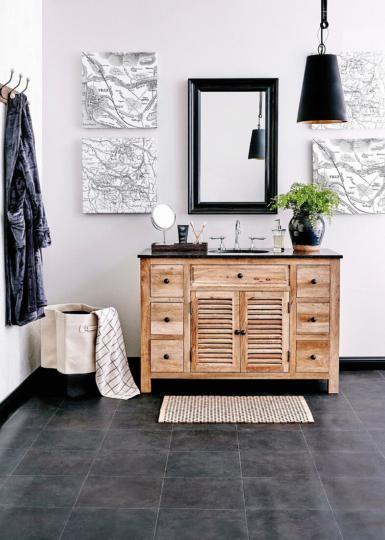 Waschtischmöbel aus Holz mit schwarzem Granitplatte, Wandspiegel und Landkarten auf Leinwand in maskulinem Badezimmer mit