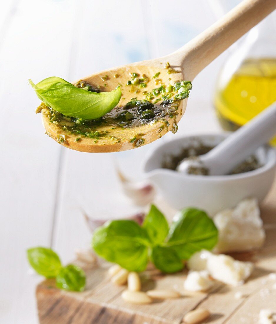 A wooden spoon with pesto and a basil leaf