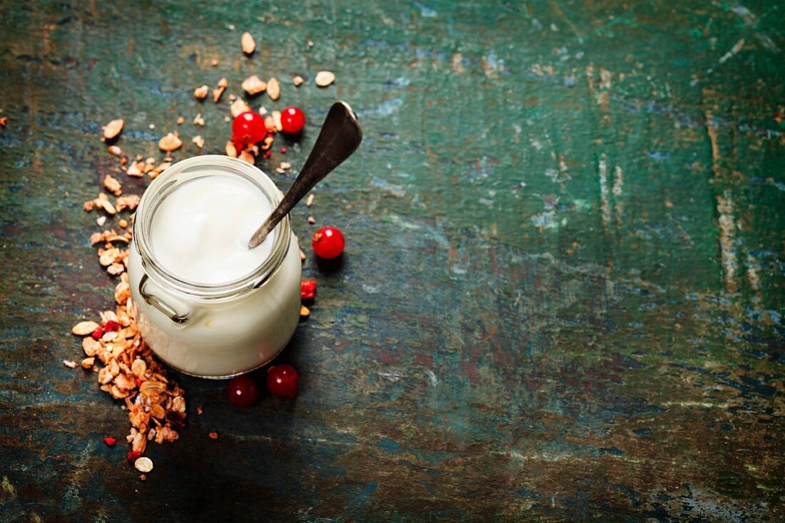 Gesundes Frühstück: Joghurt, Müsli, Beeren und Samen auf dunklem Untergrund