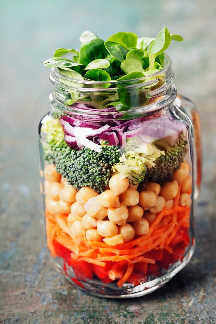 Frische Zutaten für Gemüsesalat mit Kichererbsen in Einmachglas geschichtet