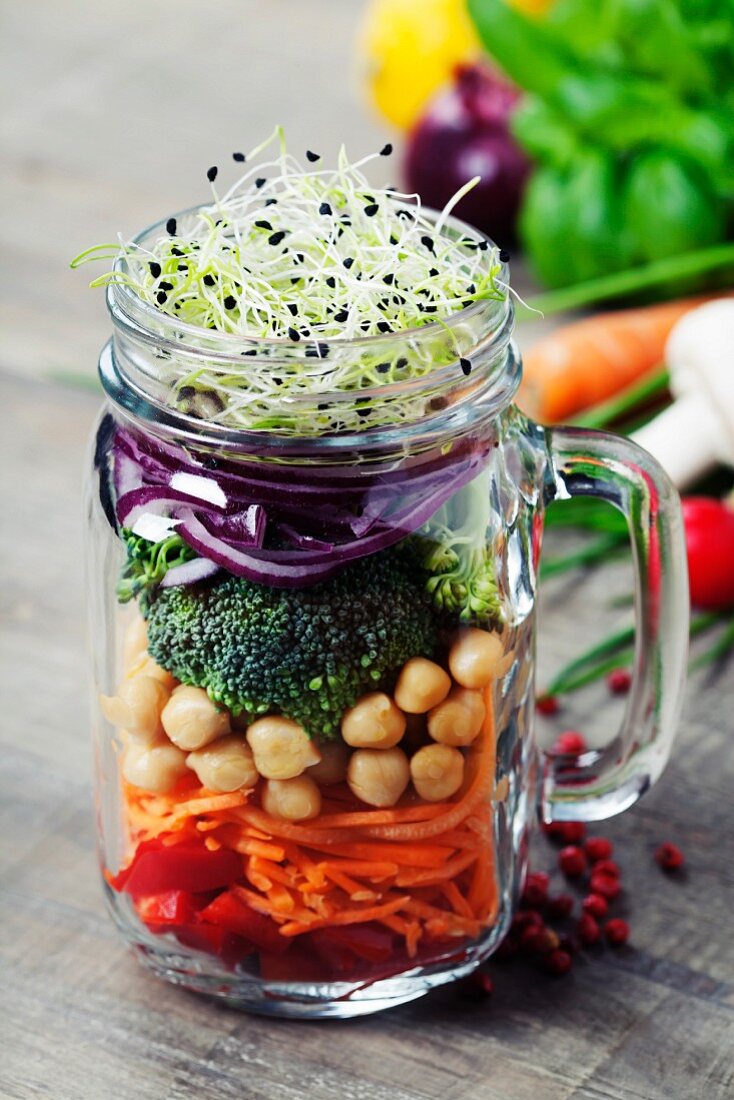 Zutaten für Gemüsesalat mit Kichererbsen und Sprossen in Henkelglas geschichtet