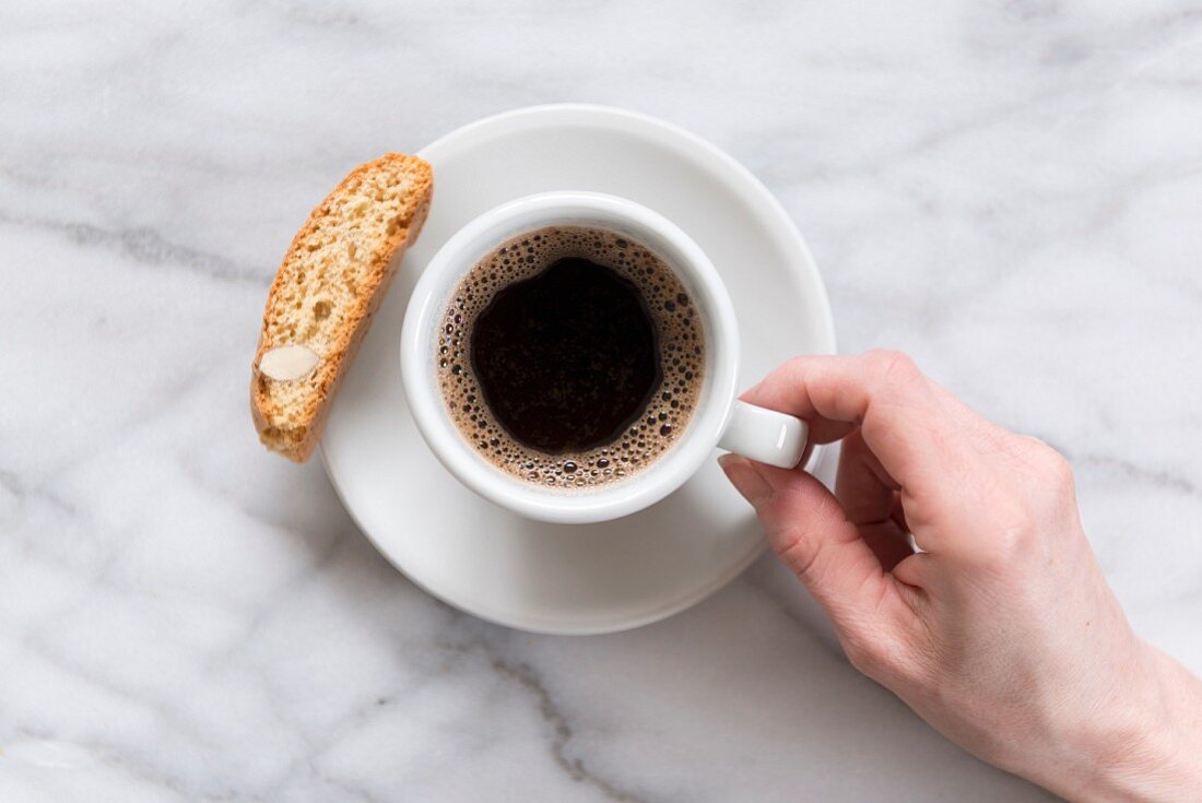 Eine Tasse Kaffee mit Biscotti auf Marmoruntergrund (Aufsicht)