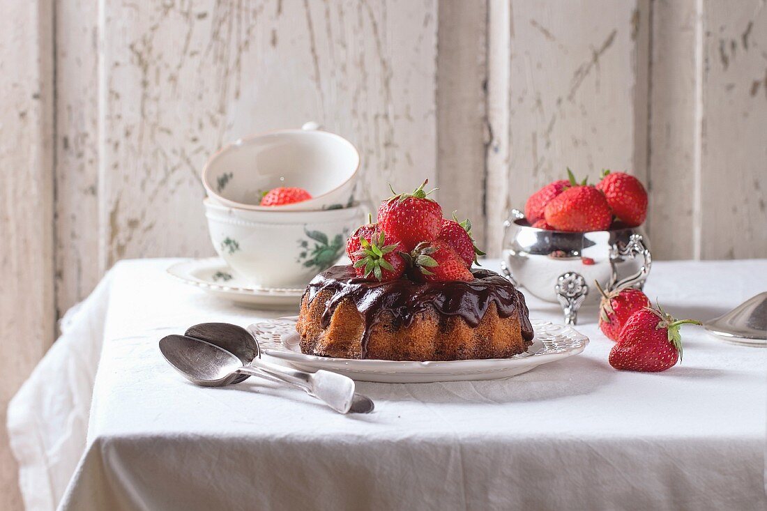 Homemade chocolate cake with strawberries and dark chocolate ganache, served on vintage plate
