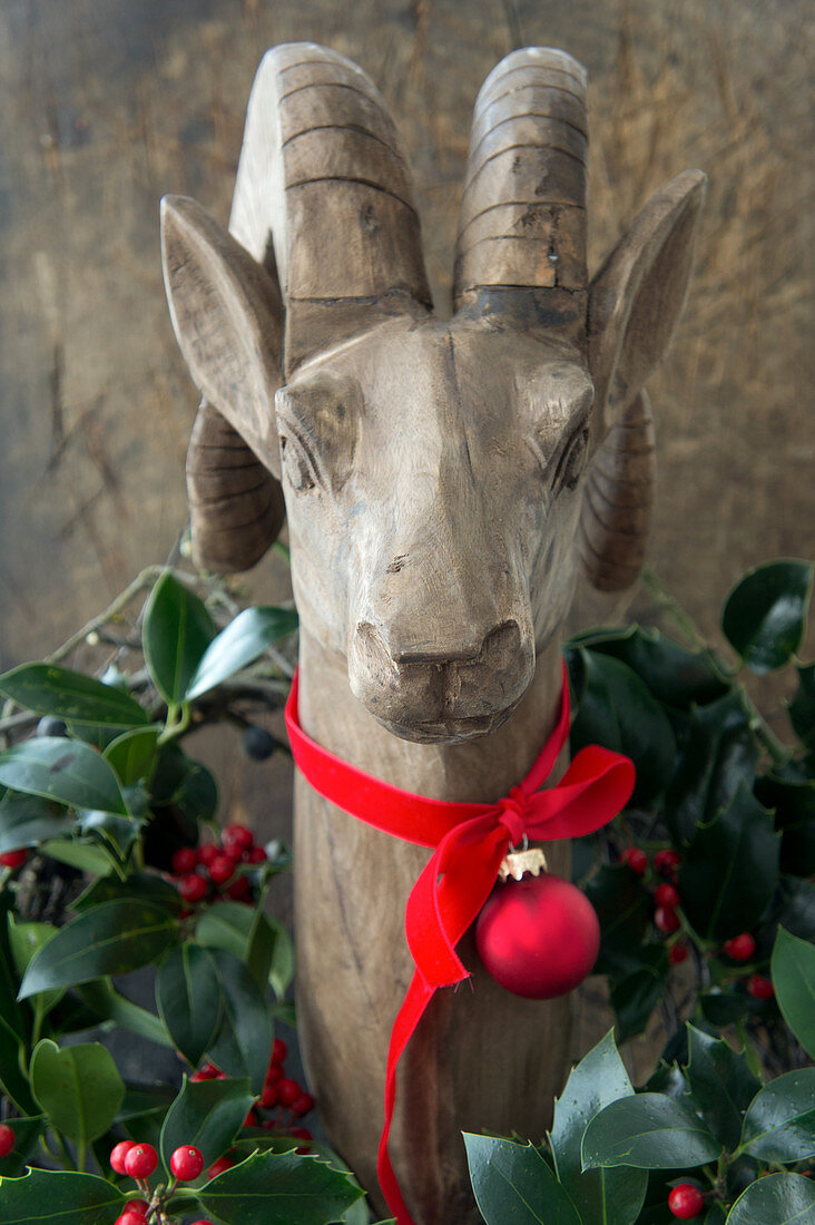 Steinbock aus Holz, dekoriert mit Kranz aus Ilex und Band mit Christbaumkugel