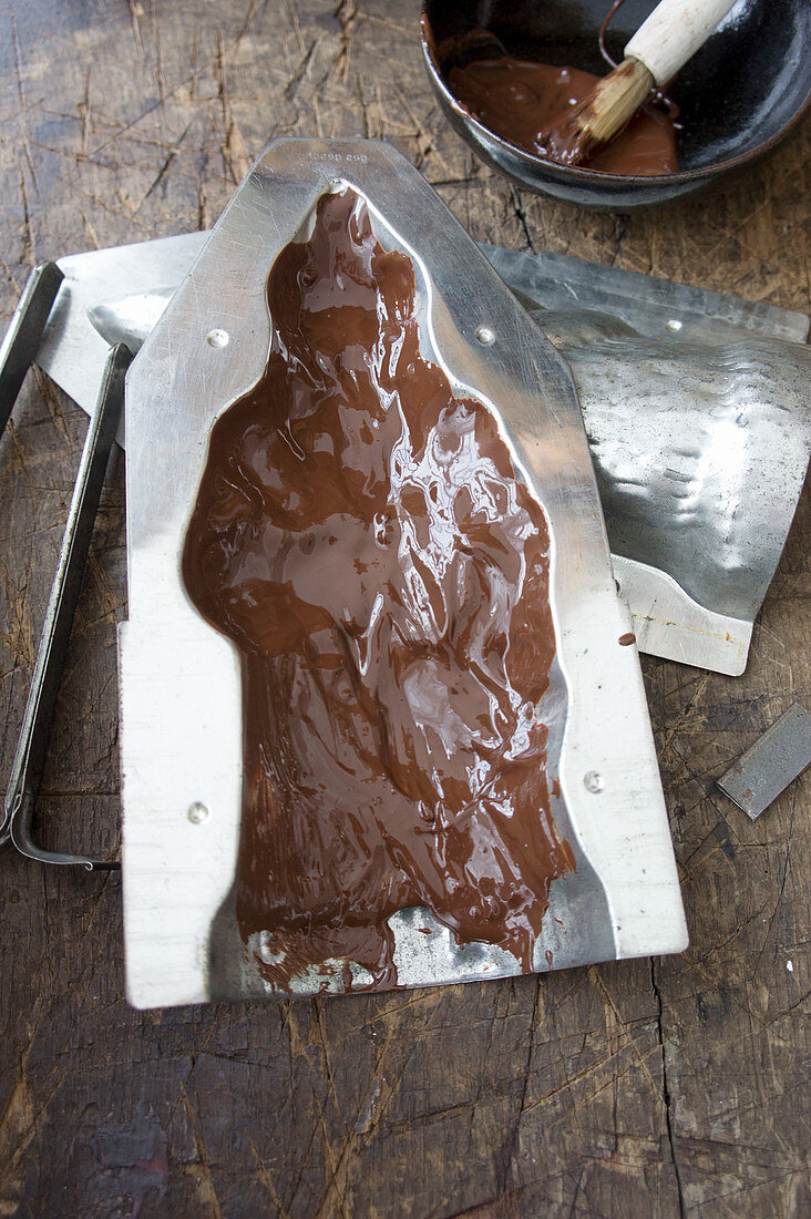 Schokoladengussform mit flüssiger Schokolade ausstreichen