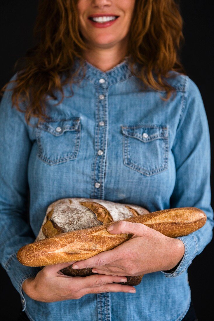 A smiling woman holding bread