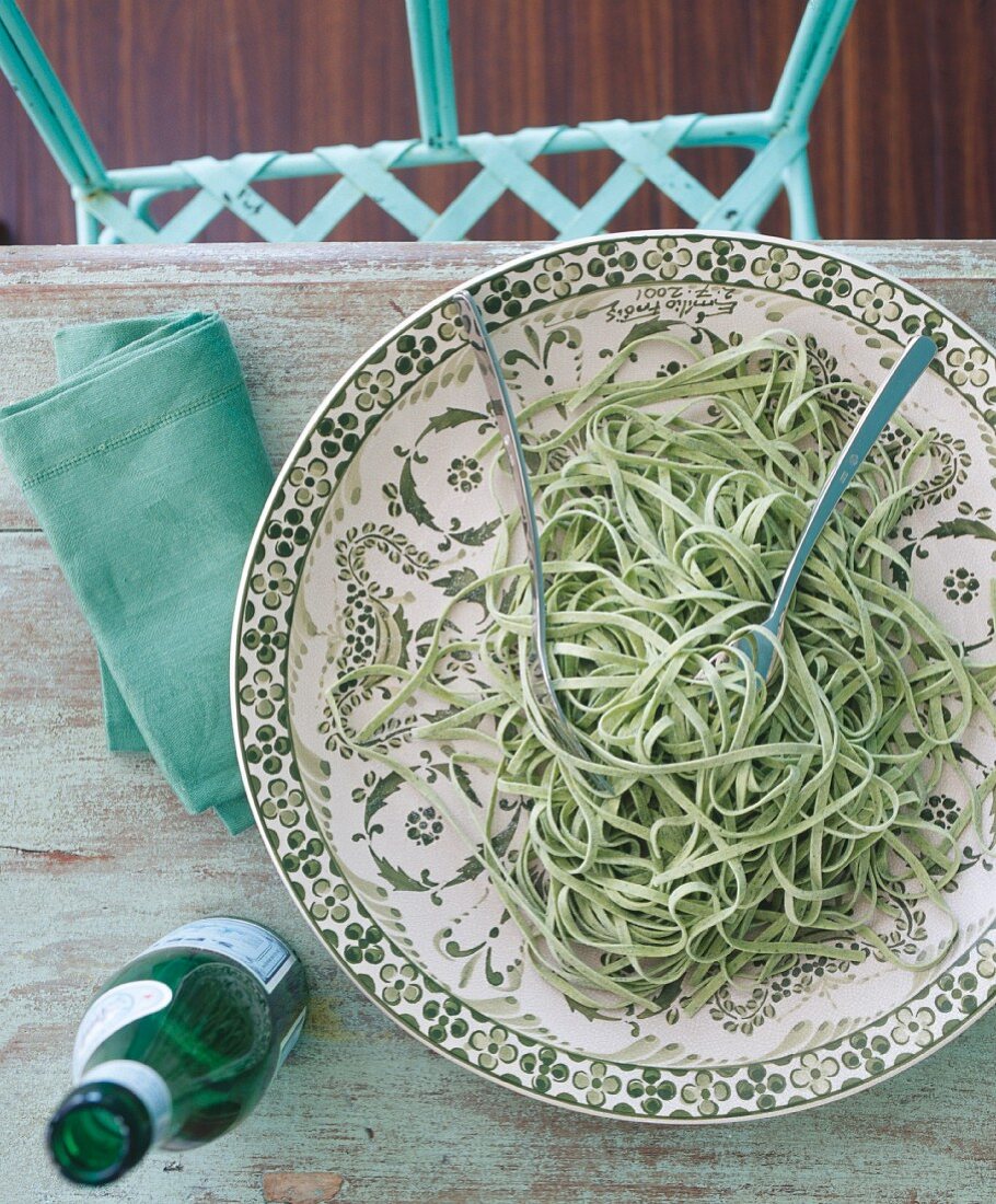 Green tagliatelle on a patterned plate (seen from above)