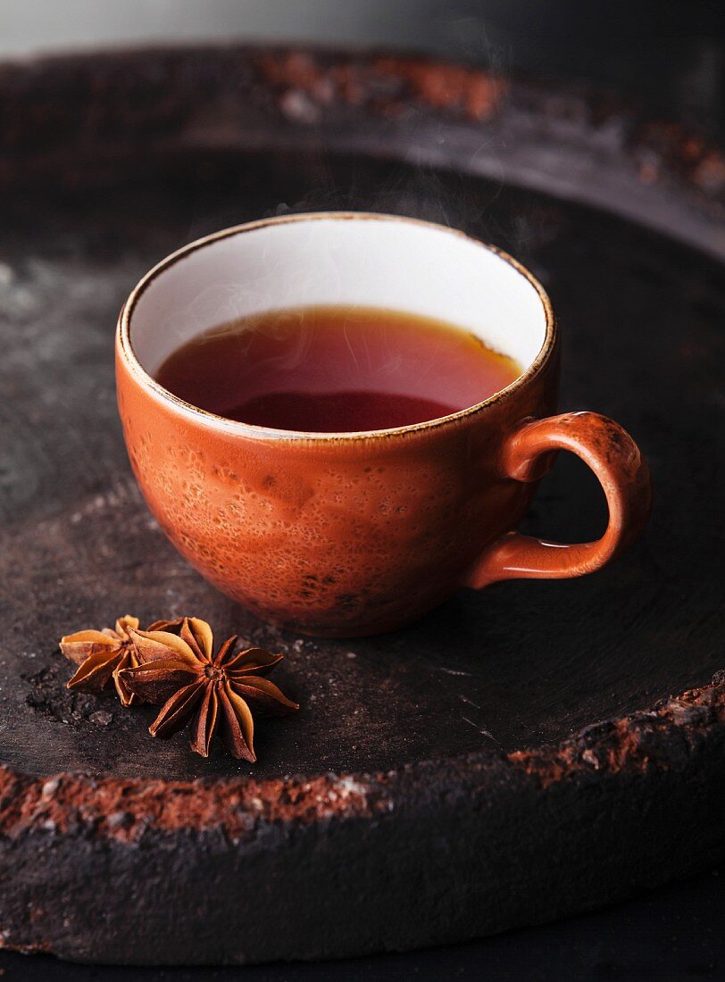 Hot tea with spices on dark background