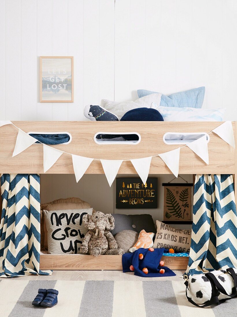 Boy's room with loft bed and white pennant chain, soft toys, pillows and sayings
