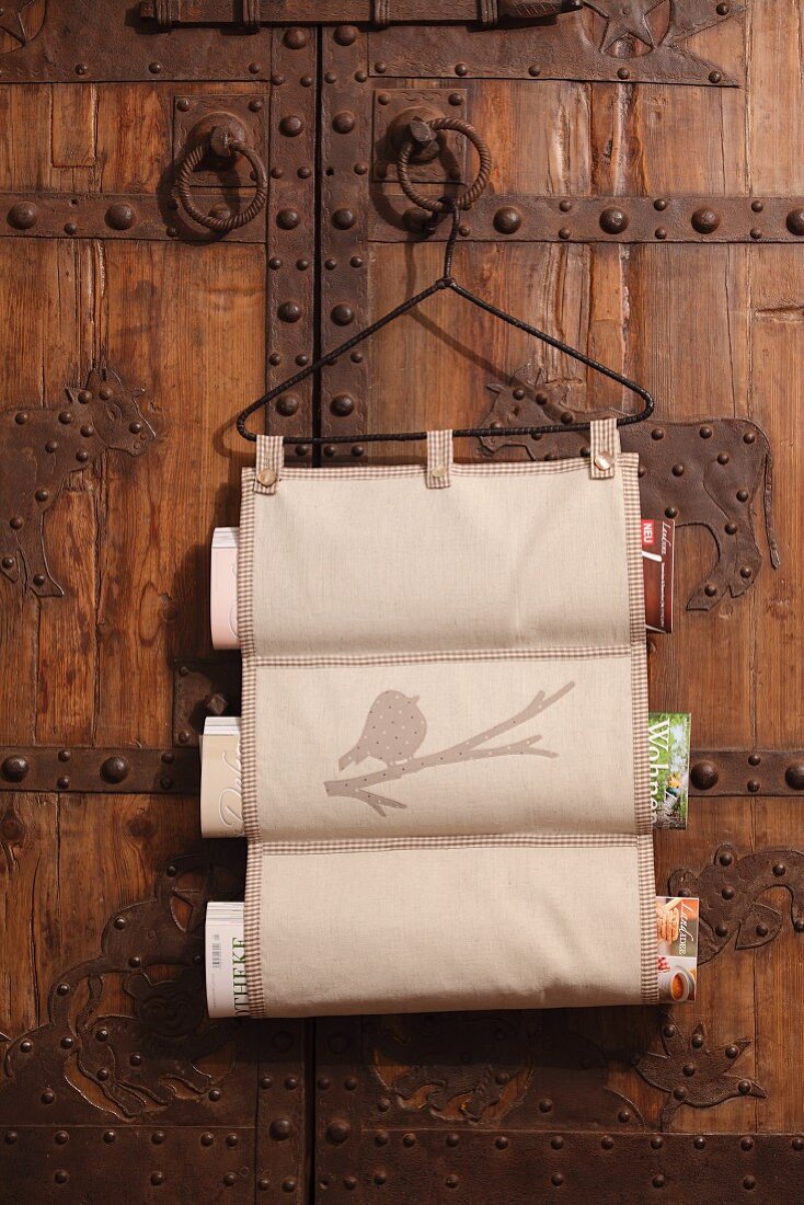 Hand-sewn magazine rack hanging from vintage coat hanger on wooden door