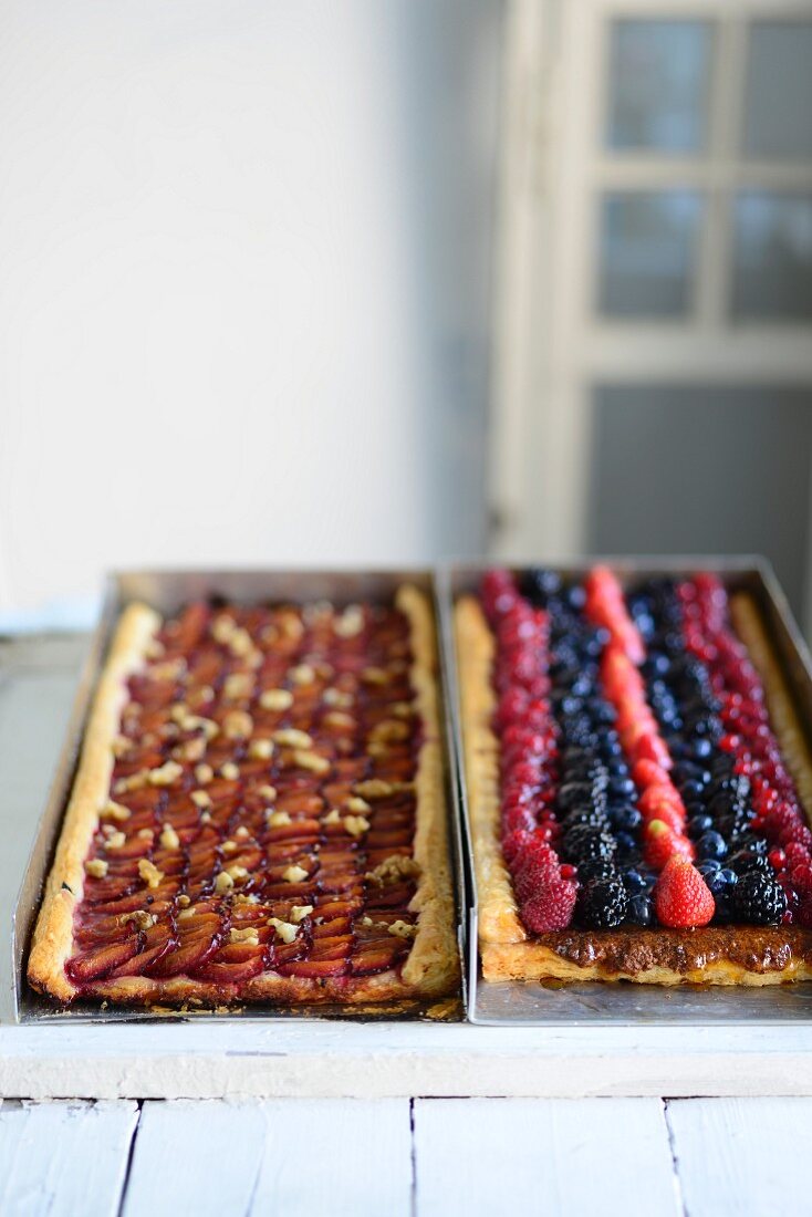 Plum cake and berry cake in baking tins