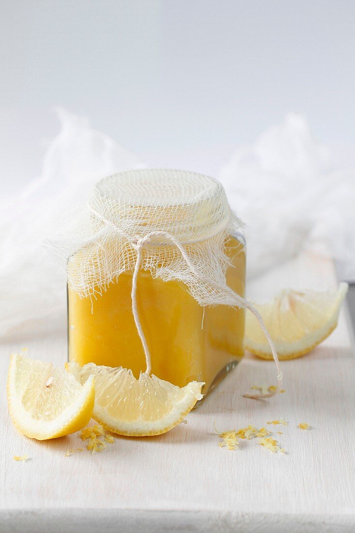 Lemon Curd im Glas mit geschnittenen Zitronen