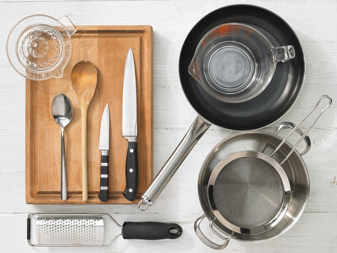 Various kitchen utensils: pot, pan, sieve, measuring cup, grater, citrus press