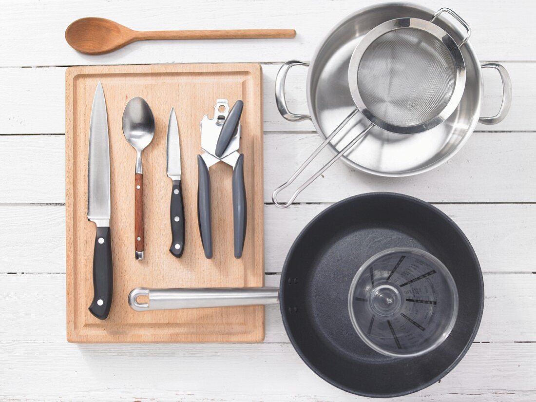 Various kitchen utensils: pot, strainer, pan, measuring cup, can opener