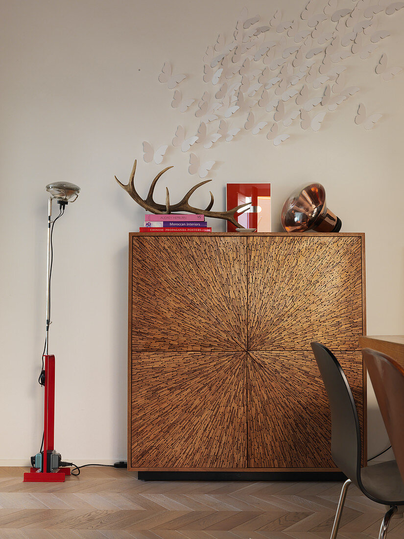 Swarm of paper butterflies on wall above cubic cabinet
