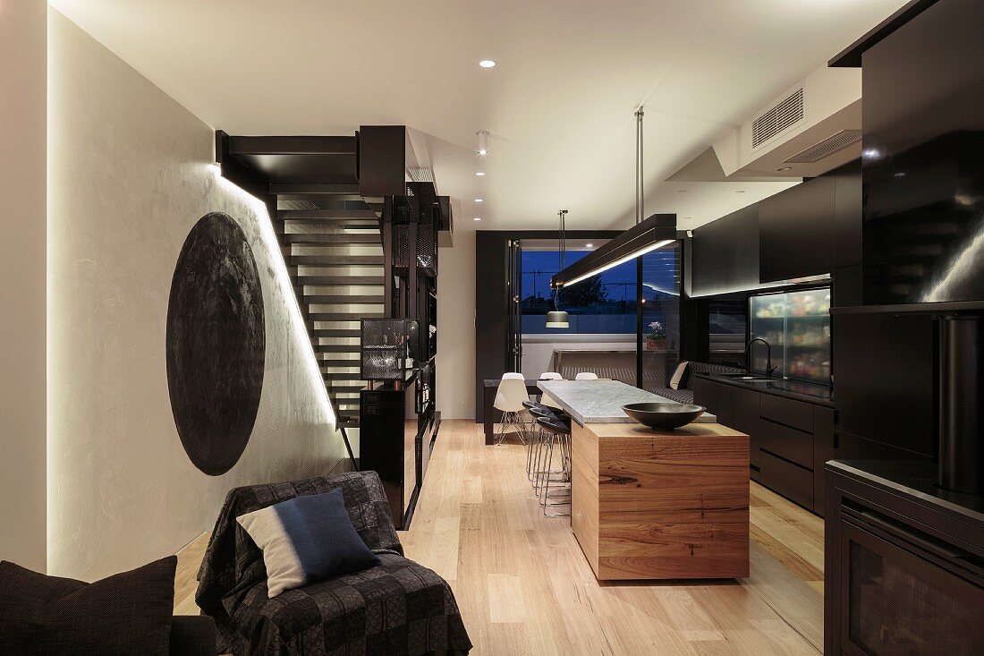 Kitchen counter and dining area next to steel staircase in black designer kitchen