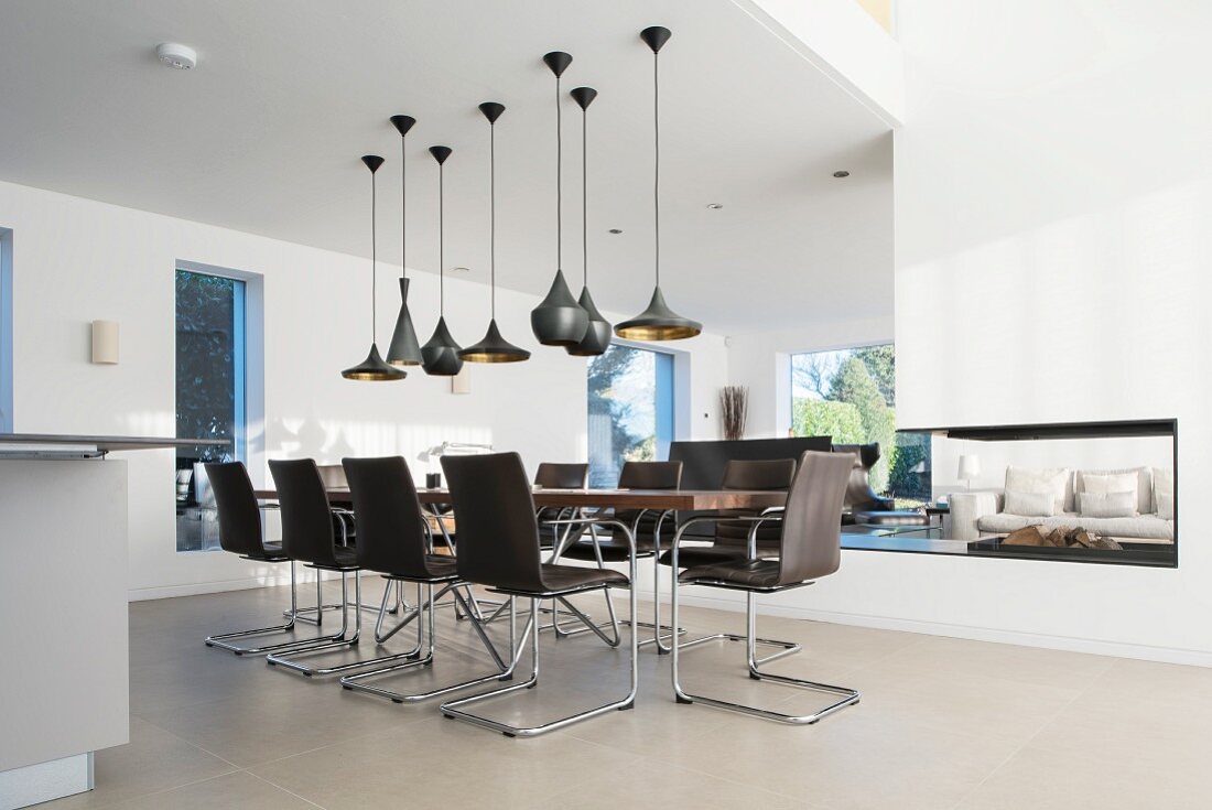 Various black pendant lamps above elegant dining table and chairs in designer apartment