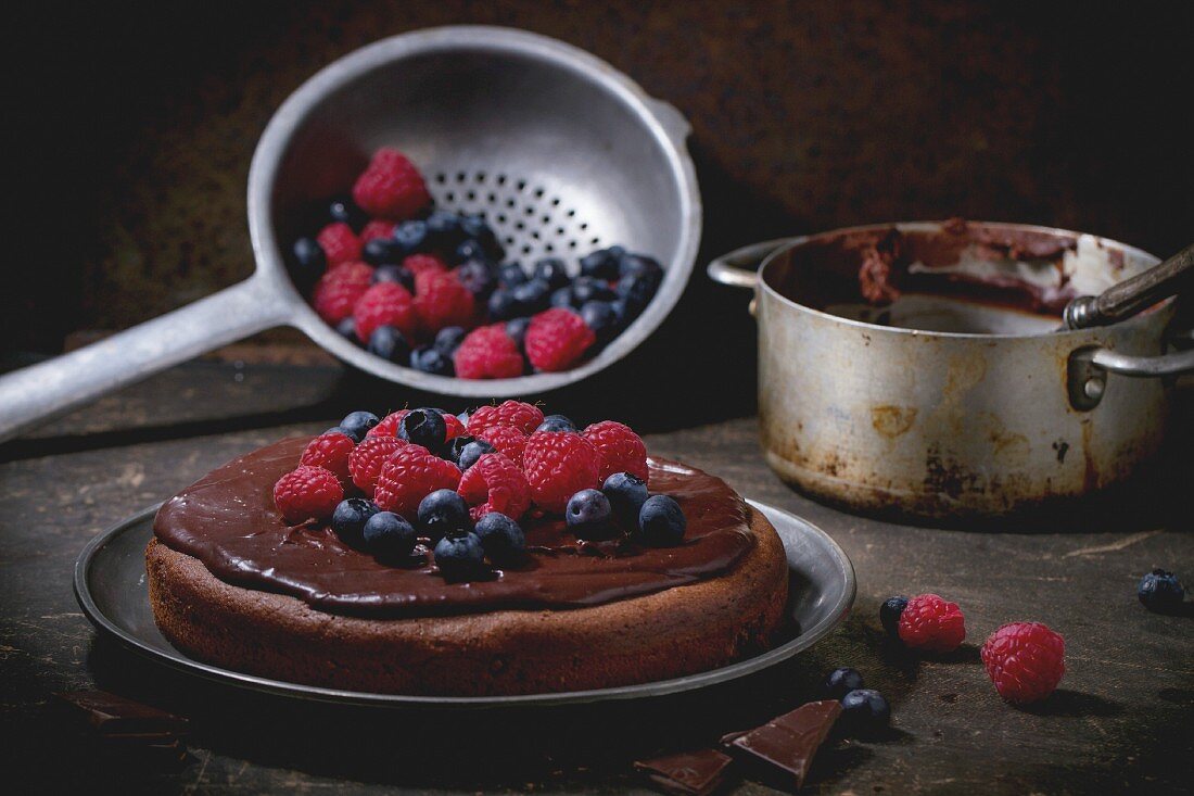 Chocolate cake with fresh berries and chocolate cream, served with vintage kitchenware