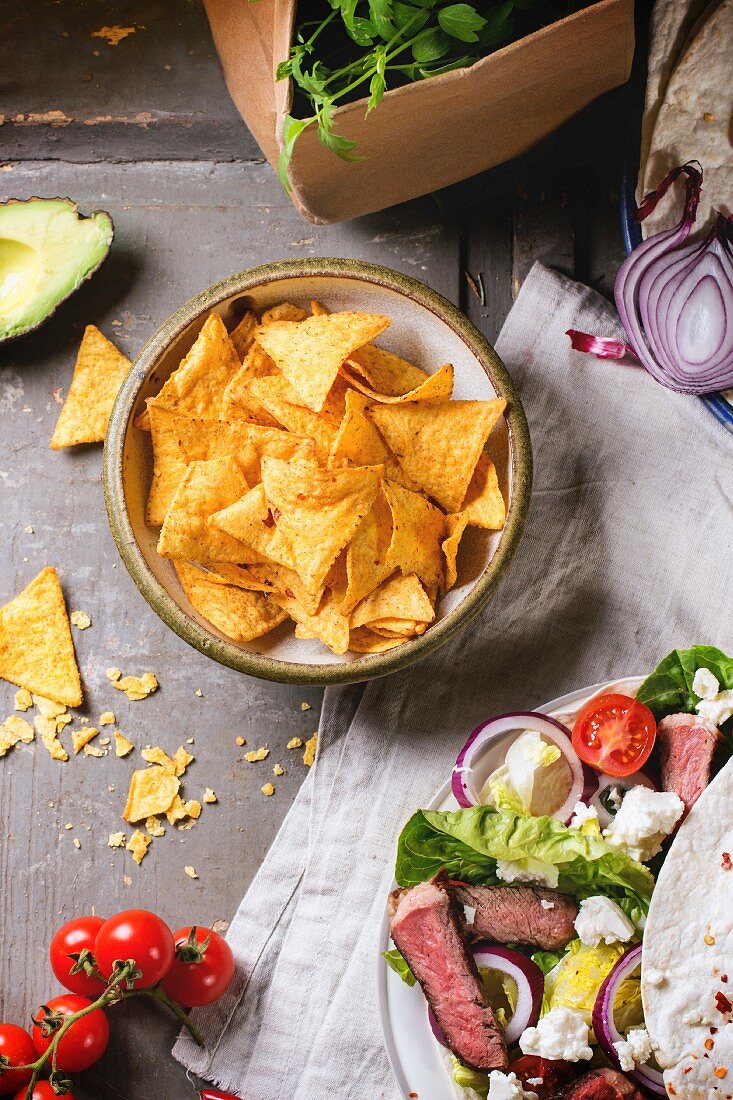 Overhead view on mexican style dinner with tacos, vegetables, nachos chips and guacamole