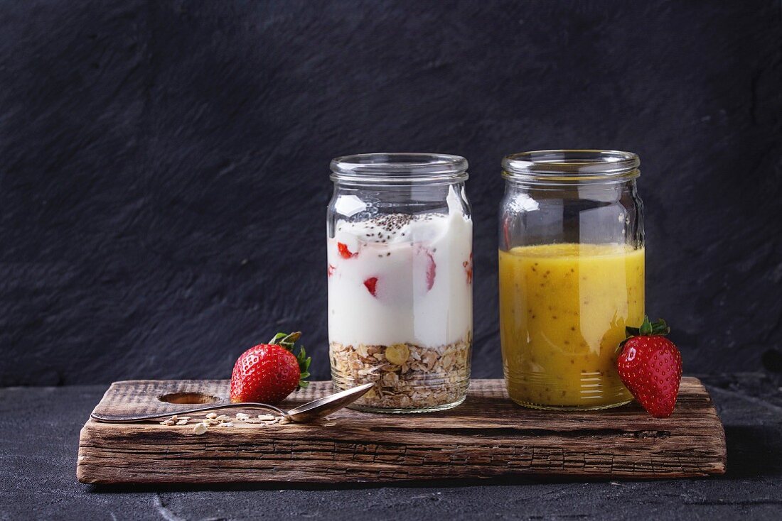 Muesli, strawberries and yogurt with mango smoothie in glass mason jars with fresh strawberry