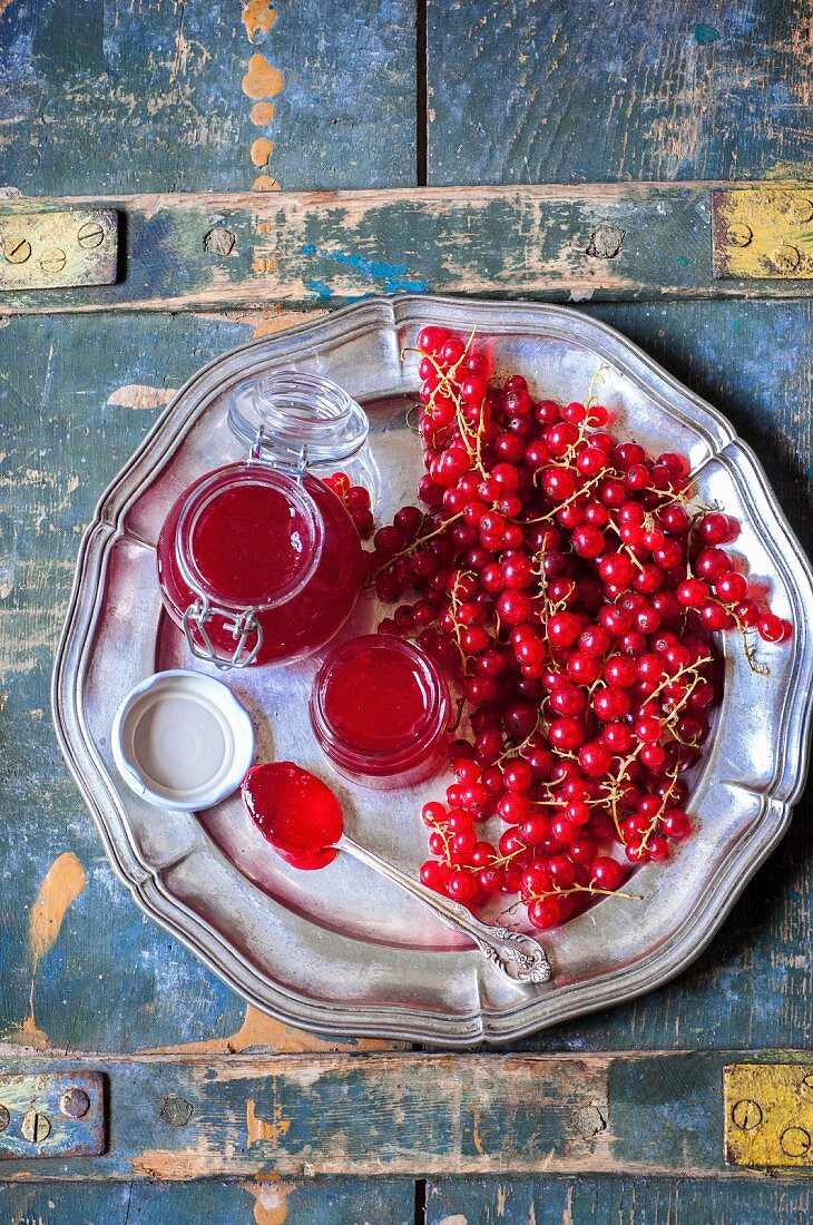 Redcurrant jam in glass jars on a metal plate