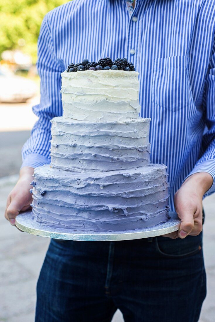 A man holding a three-tiered wedding cake