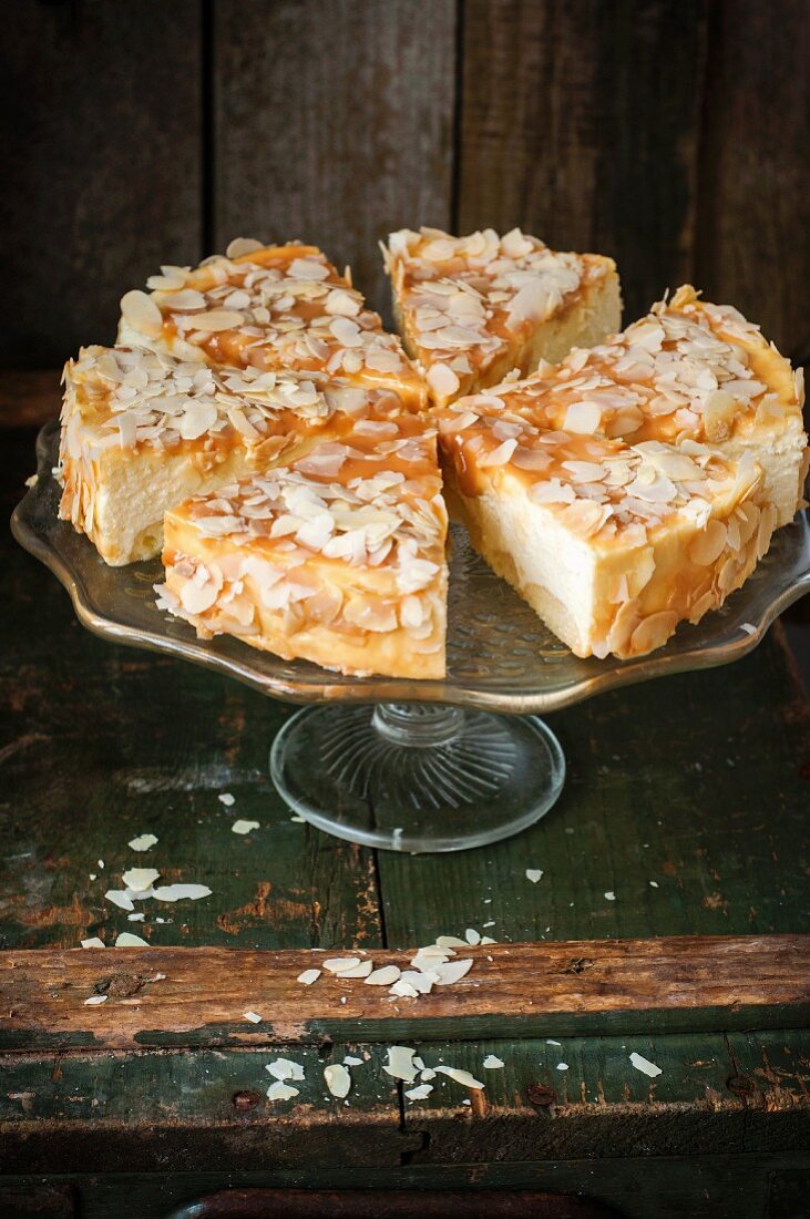 A cheesecake covered in caramel glazing and almond flakes