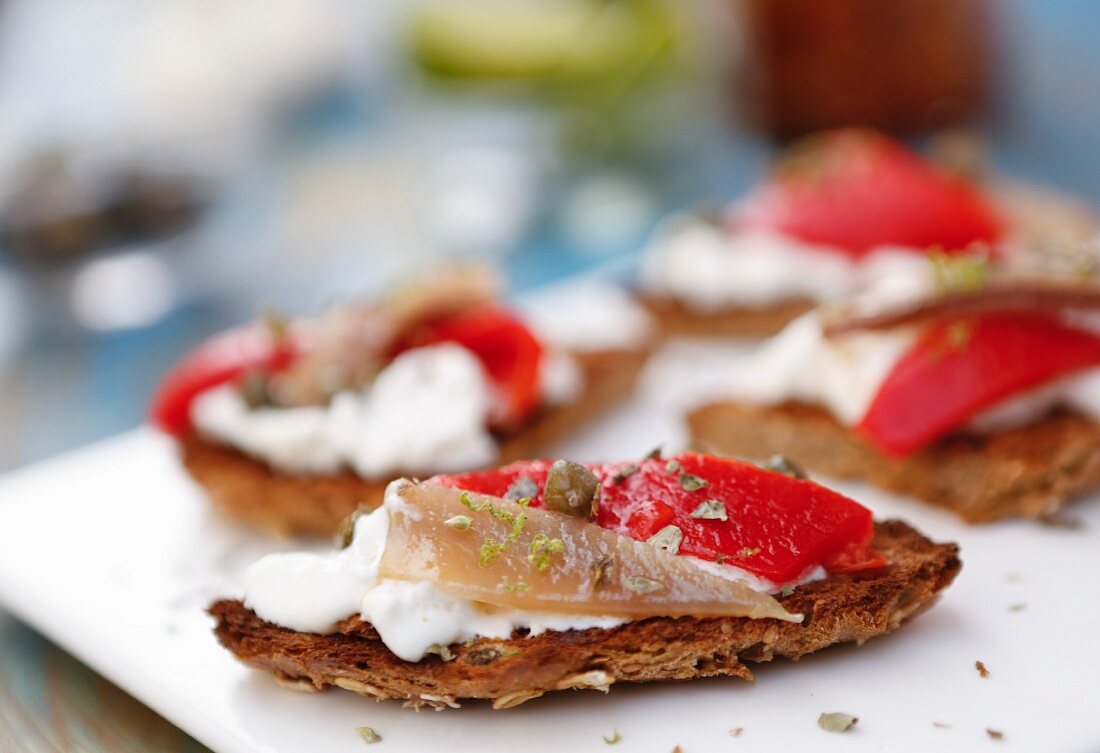 Bruschetta mit Frischkäsecreme, Anchovis, Paprika, Oregano und Limettenzesten